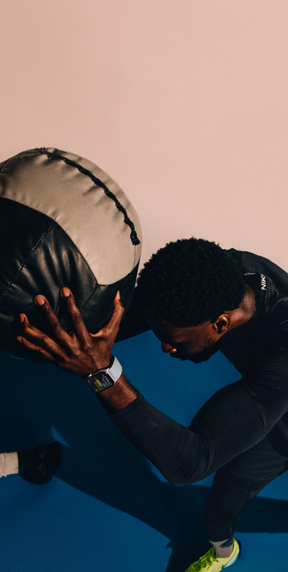  A man wearing an Apple Watch Series 10 is exercising. He is lifting a medicine ball.