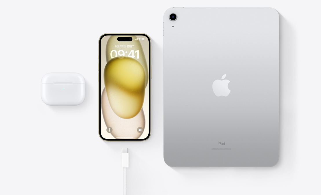 AirPods Pro、iPhone 15 和 iPad，以及一条 USB-C 接口连接线的俯视图，展示三部设备都能够通过同一条 USB-C 连接线充电。