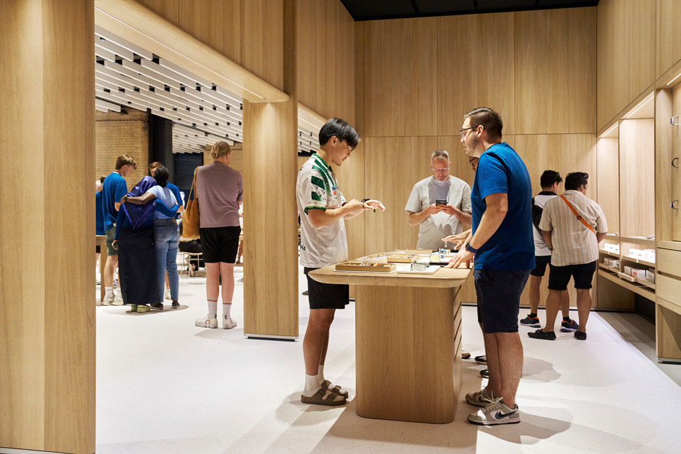 伦敦 Apple Battersea 零售店内，一位顾客在团队成员协助下探索 Apple Watch 定制坊。