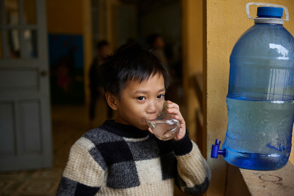 Vay Nua 少数民族中小学寄宿学校的一名学生正在饮用 Gravity Water 系统过滤后的水。