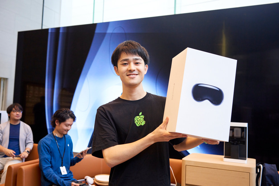 Apple 表参道零售店内，一位顾客举起他购买的 Apple Vision Pro。