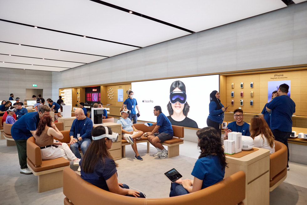 远景照片显示，Apple 乌节路零售店的 Demo Zone 演示区内，顾客和团队成员在弯曲的长椅上就坐。