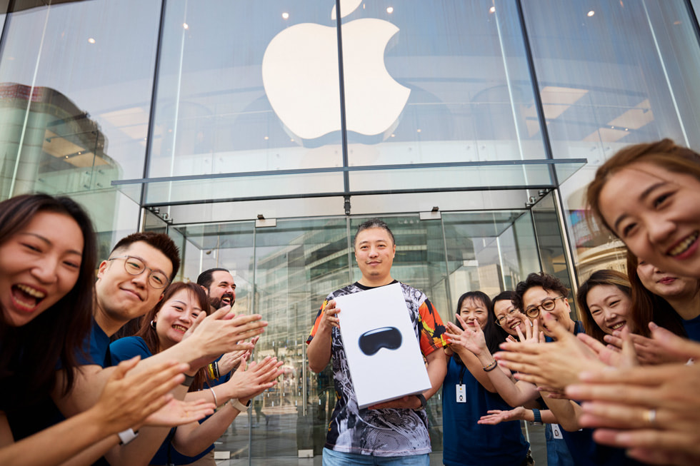 一位顾客带着 Apple Vision Pro 走出 Apple 王府井零售店，团队成员热烈欢呼。
