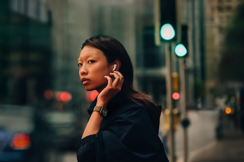 一个人佩戴着 AirPods 4 和 Apple Watch Series 10 站在城市街头。