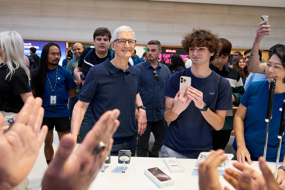 Tim Cook 笑着与纽约 Apple 第五大道零售店顾客和团队成员合影。