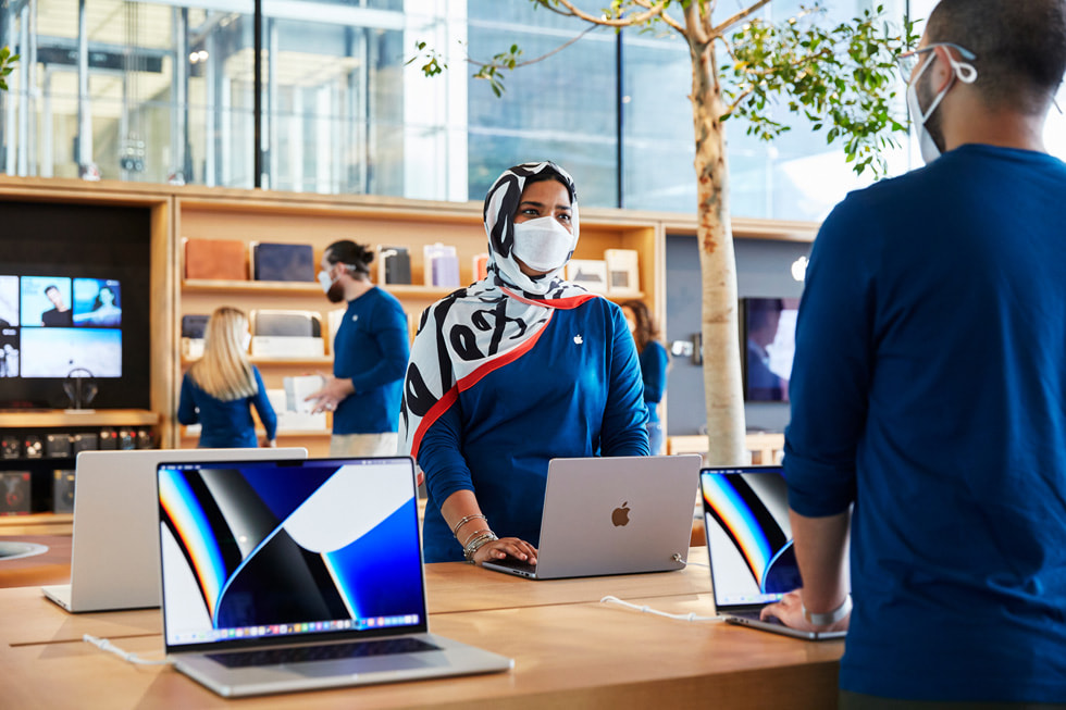 Apple Al Maryah Island 零售店团队成员正在店内设置 MacBook Pro 展示桌。