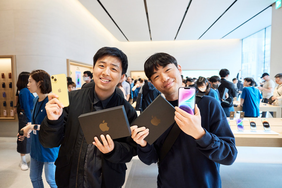 Apple Gangnam 零售店内，顾客手持全新 iPhone 14。