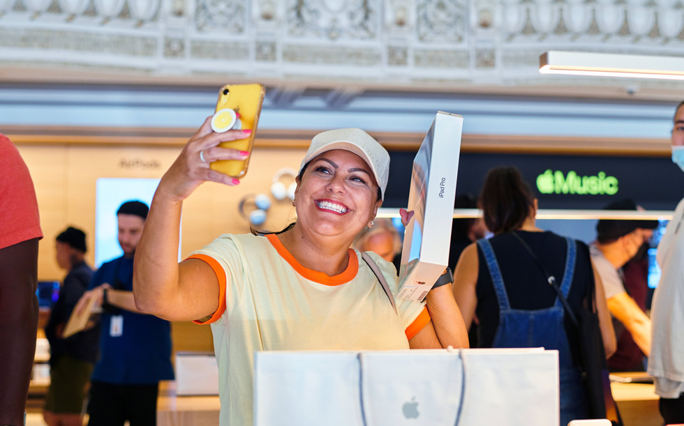 一名顾客在 Apple Tower Theatre 自拍照片，庆祝自己购买了新 iPad Pro。
