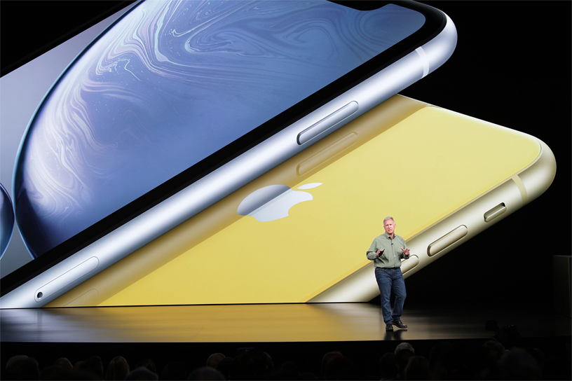 Phil Schiller 在以 iPhone XR 图片为背景的演讲台上。
