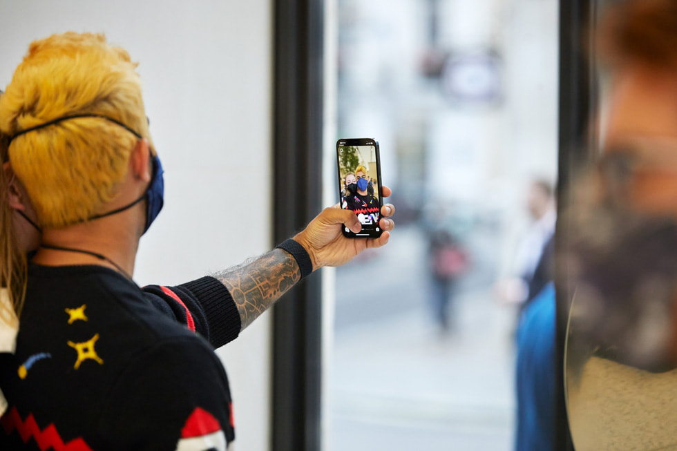 Apple Regent Street 零售店内，顾客正在使用新款 iPhone 13 Pro 自拍。