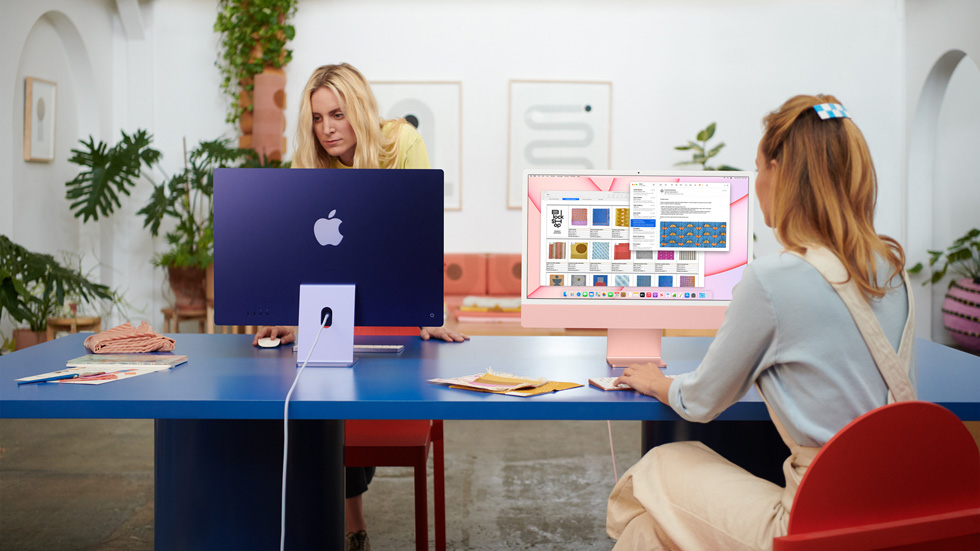 两名女性在共享工作空间里使用她们的 iMac。
