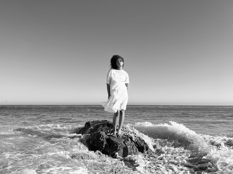 使用 iPhone 13 Pro 广角镜头配合传感器位移式 OIS 功能拍摄的站立在海边的女子。