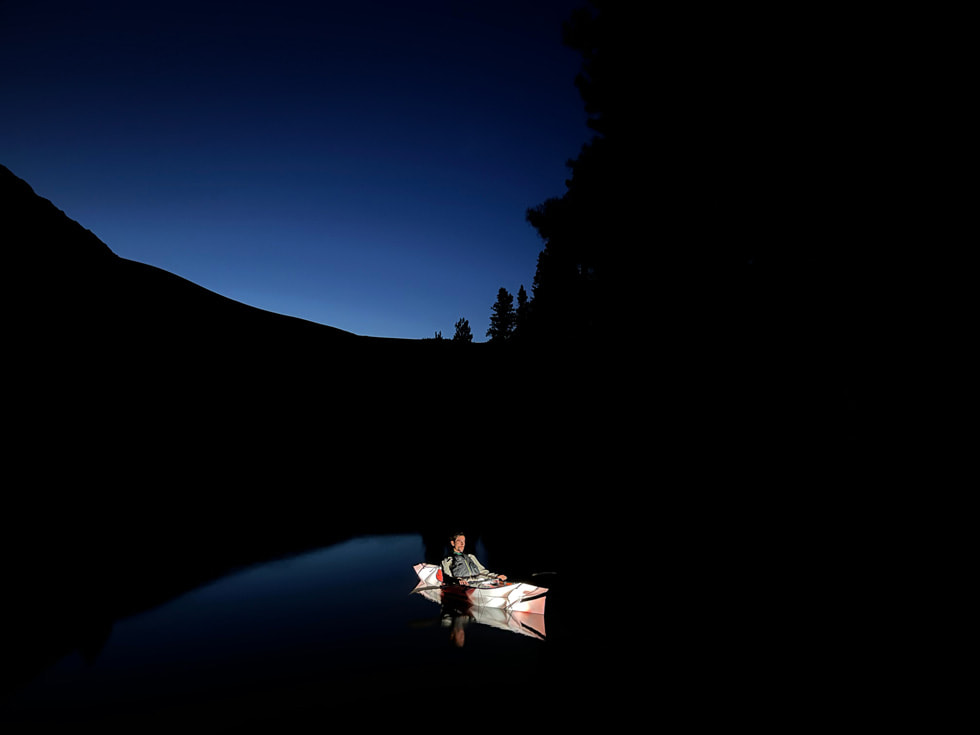 使用 iPhone 13 的广角摄像头夜间模式在夜间拍摄的独木舟中的男子。