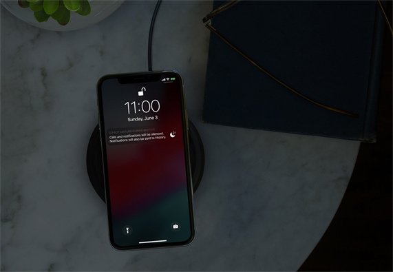 黑暗房间内使用无线充电器的 iPhone 屏幕上显示勿扰模式。