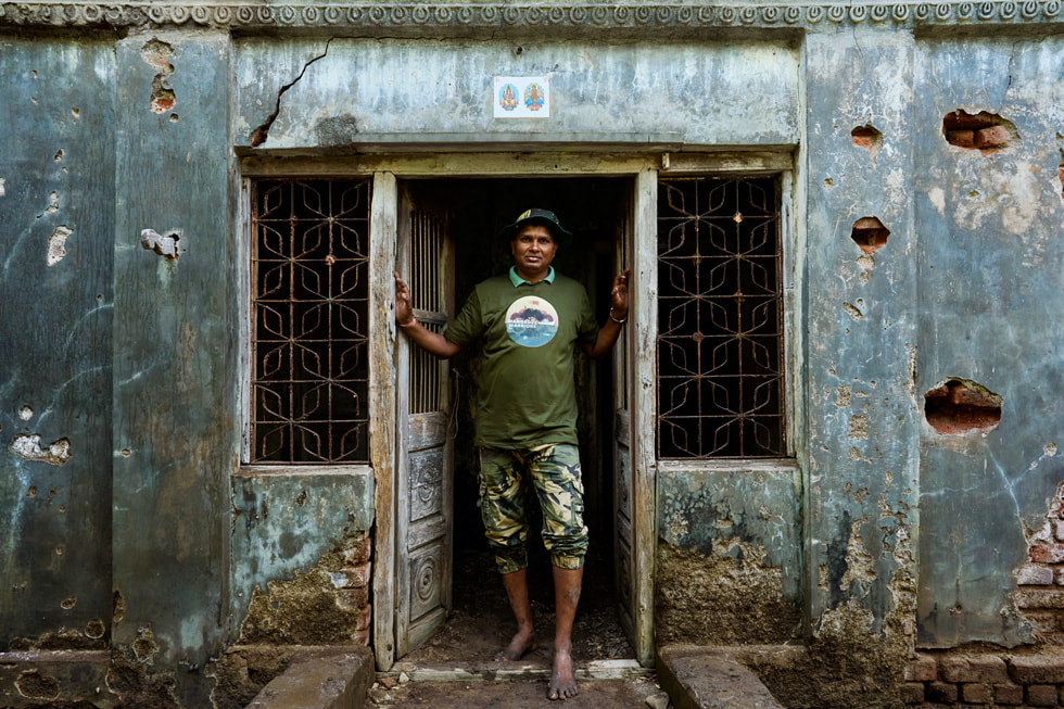 在 Ganesh Patti 村，渔民 Mangesh Patil 站在一所建筑的门外。